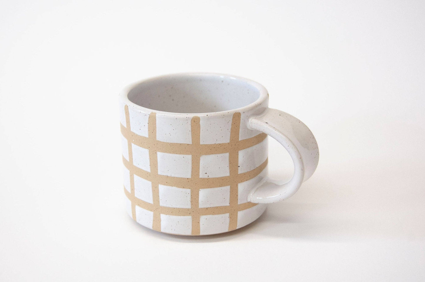 Ceramic mug with beige checkered pattern on a white background