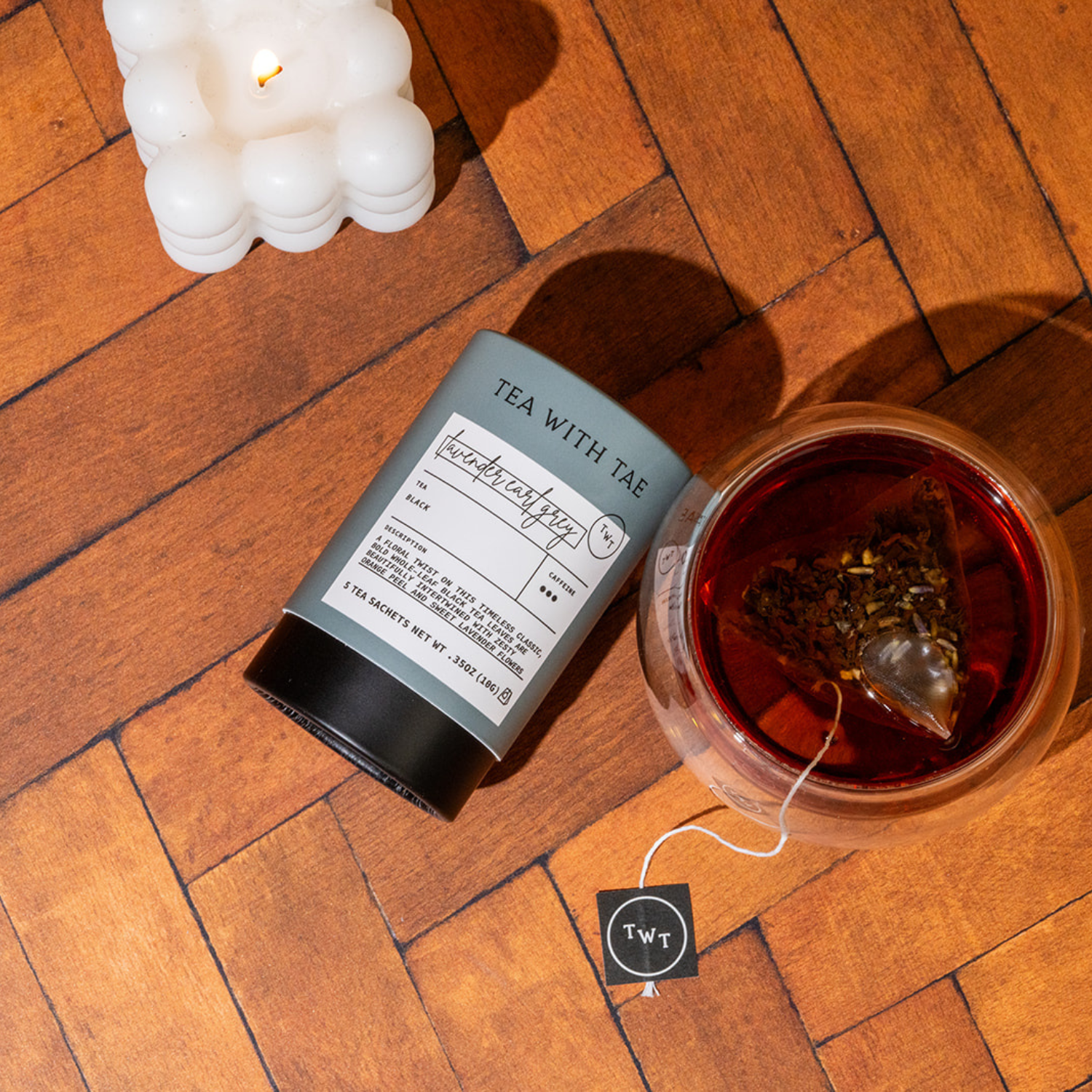 Tea packaging with a tea bag on a wooden surface next to a glass of tea.