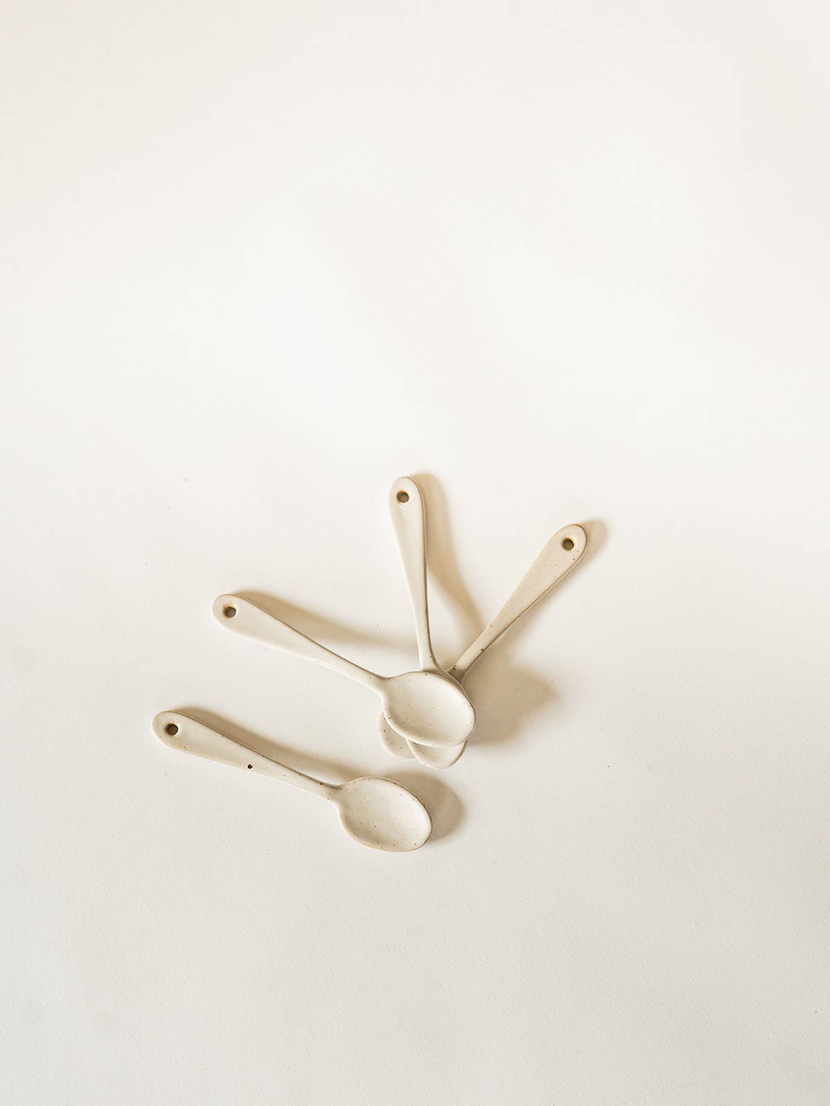 Three ceramic measuring spoons on a light beige background