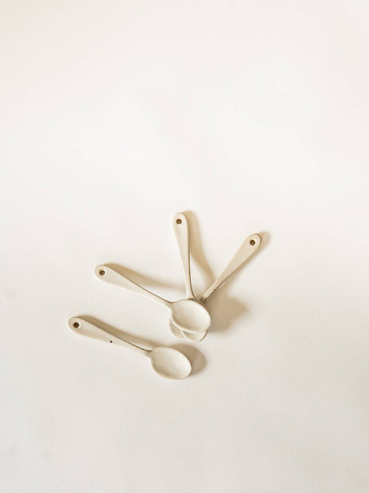 Three ceramic measuring spoons on a light beige background