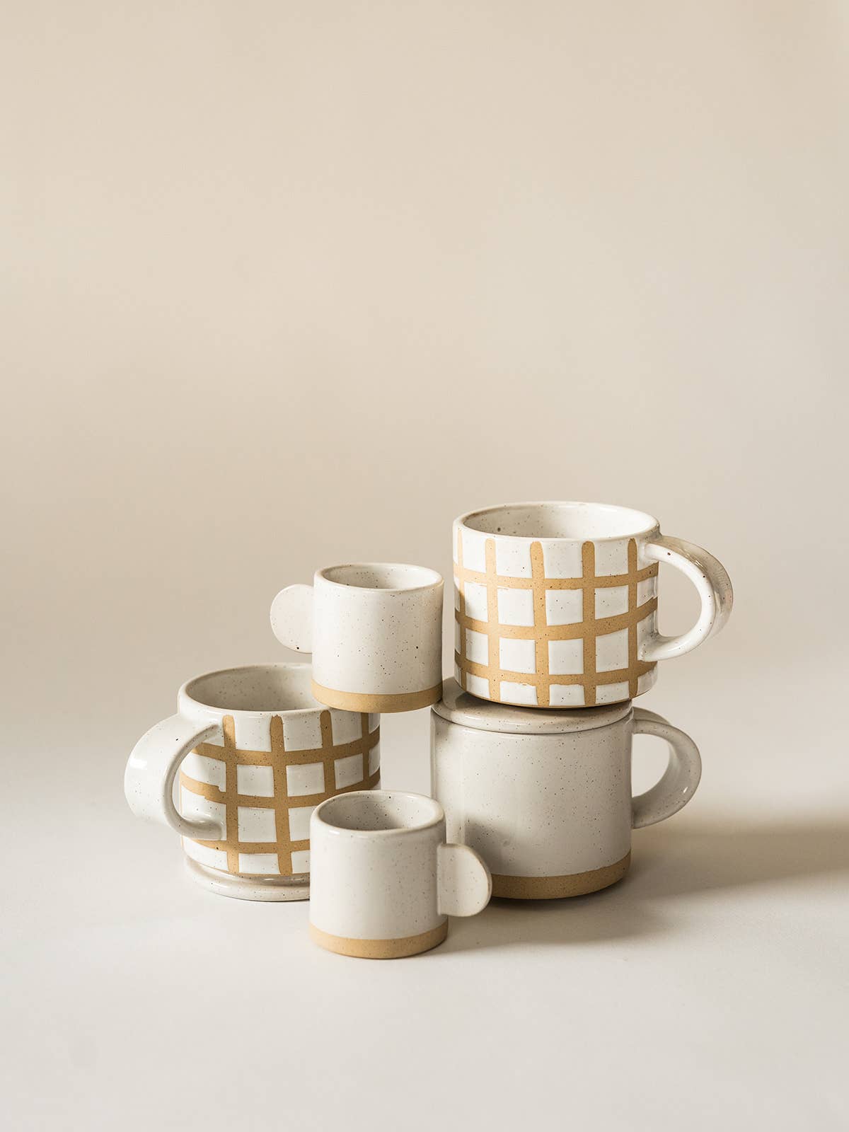 Set of ceramic mugs with grid pattern on a beige background